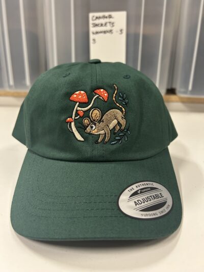 a photograph of a forest green hat with a mouse and mushrooms stitched on.
