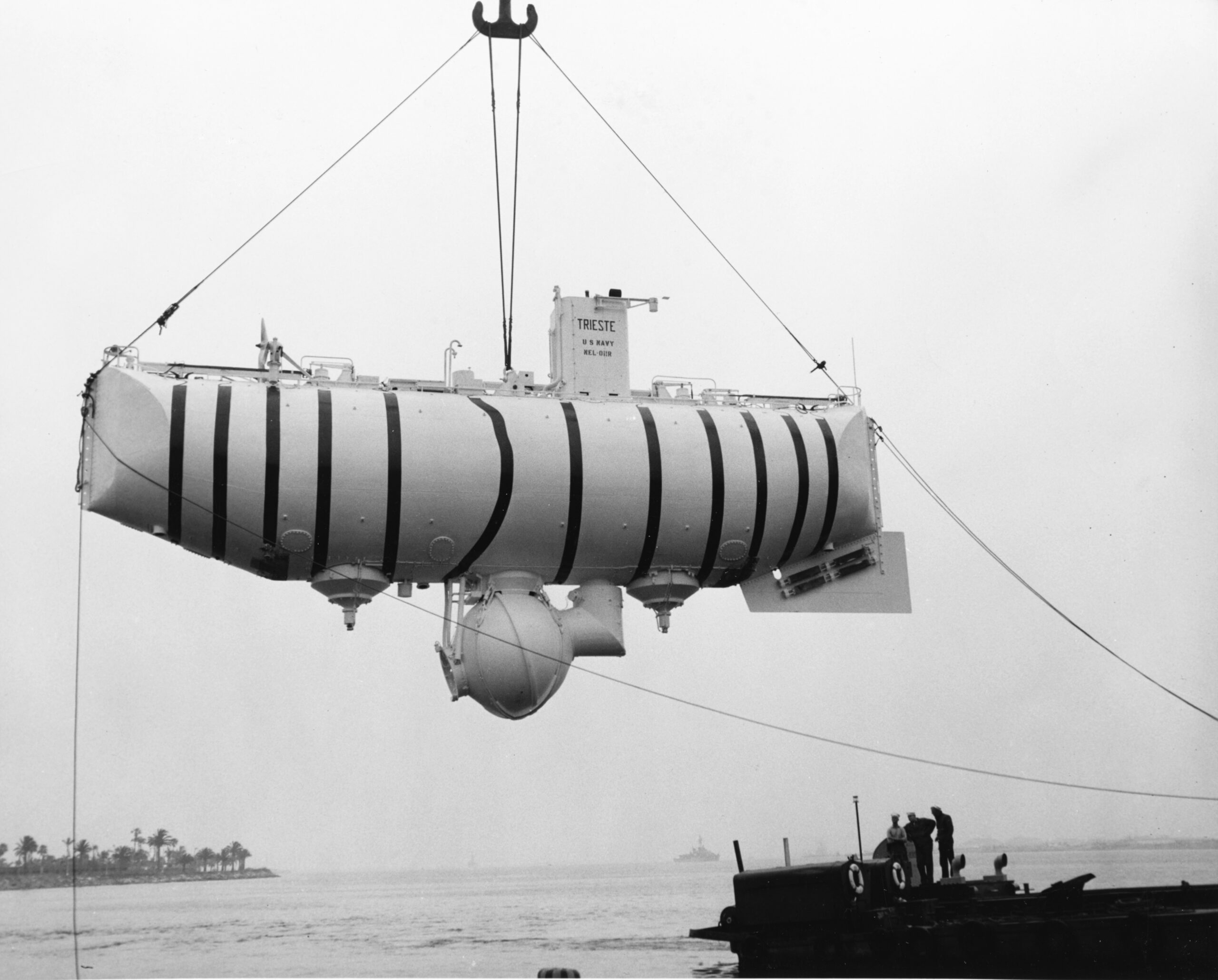 Black and White photograph of an underwater submersible being lifted into the air before being dropped into the ocean.